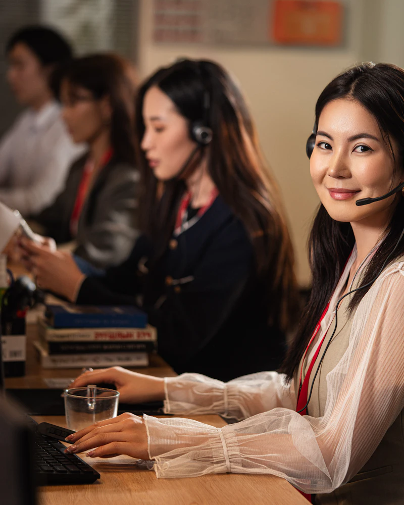 A dispatcher wearing a telephone headset at a computer, turning to look at the camera.